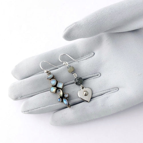 asymmetric earrings in silver and blue colours containing Labradorite and Blue Moonstone displayed on a gloved hand