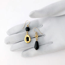 Load image into Gallery viewer, black and gold cameo earrings with black and gold beads displayed on a gloved hand
