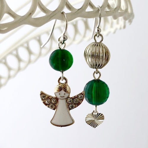 asymmetric earrings in silver and green with a rhinestone set angel charm