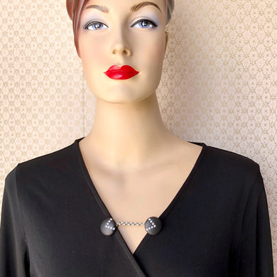 mannequin in a black wrap dress with a black and rhinestone set sweater guard