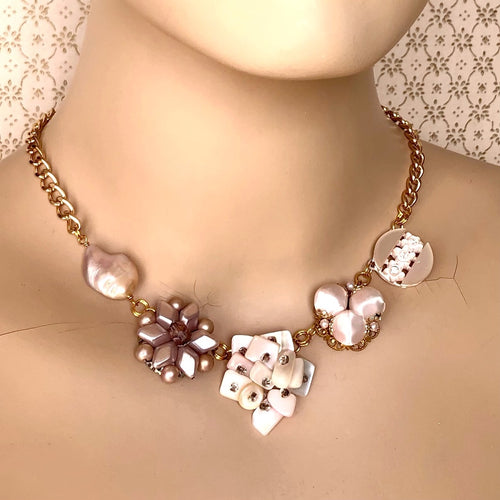 necklace in soft pinks made with vintage earrings, necklace link and freshwater pearl displayed on a mannequin