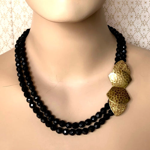 double stranded necklace of black facetted beads and brass belt buckle clasp displayed on a mannequin