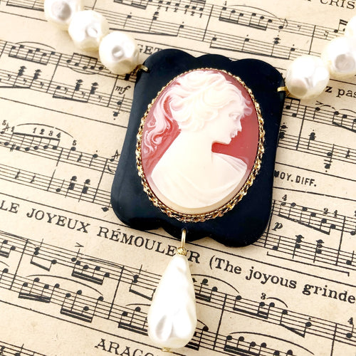 close up of cameo focal and pearlised beads on vintage music paper