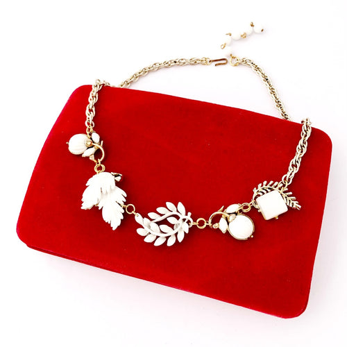 necklace with five white leaf or flower shapes on a red velvet jewellery box