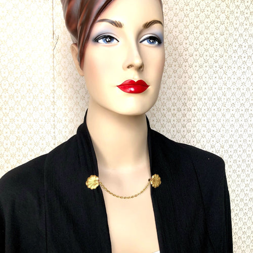 mannequin wearing a cardigan secured by a sweater guard made from vintage lily pad stampings