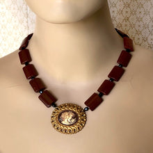 Load image into Gallery viewer, a cameo necklace featuring two women and a bird, with chocolate brown and black beads on a mannequin
