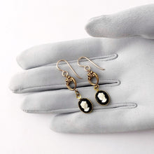 Load image into Gallery viewer, earrings made with vintage black and white cameos  displayed on a grey gloved hand
