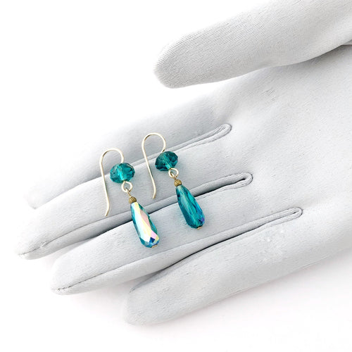 teal glass drop earrings on a gloved hand