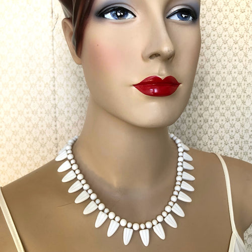 mannequin wearing a white articulated necklace with petal shaped beads